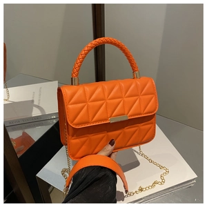 Close-up of orange quilted handbag with woven handle and gold metal twist lock