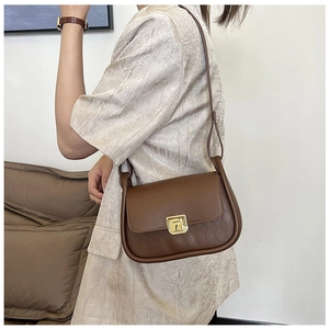 Close-up of a brown leather crossbody bag featuring quilted texture and a gold metal clasp
