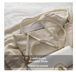 Close-up of stylish white leather shoulder bag featuring a gold circular swivel lock