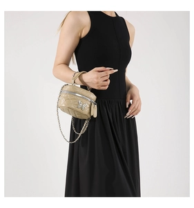 Close-up of quilted beige mini box bag with silver butterfly clasp and chain strap