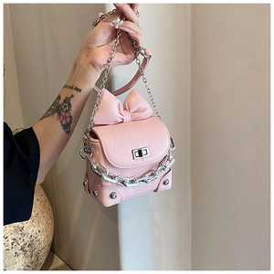 Detailed view of pink crossbody bag with large bow, pleated texture and silver chain