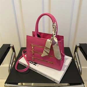 Detail of fuchsia square handbag with triple gold zippers and silk scarf handle