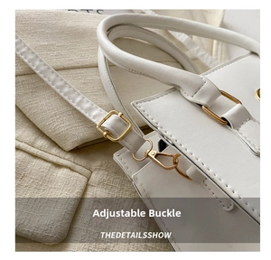 Close-up of the adjustable strap buckle and gold hardware on a white leather handbag