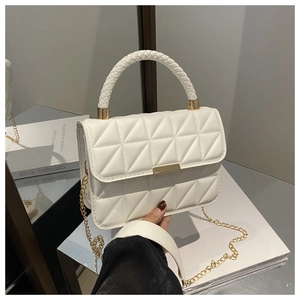Detailed view of white quilted bag featuring woven handle and gold metal chain strap