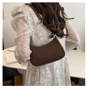 Detail of dark brown quilted shoulder bag with chain strap and V-shaped stitching