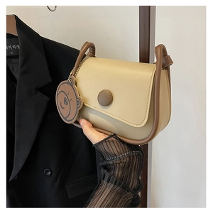 Vue détaillée du sac besace beige avec bordure marron et pendentif ours mignon