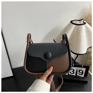 Detail of two-tone crossbody bag featuring wavy flap design and contrast stitching
