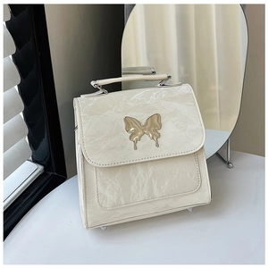 Detail of cream white leather handbag featuring a golden butterfly metal buckle and soft texture