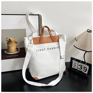Detail of canvas tote bag showing brown leather handles and adjustable shoulder strap