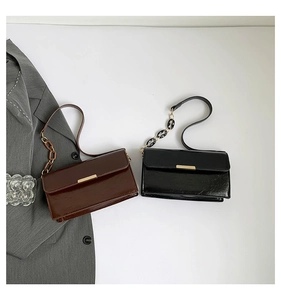 Flat lay of vintage glossy leather shoulder bags in black and brown with chain detail