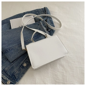Details der weißen Mini-Tasche aus Kunstleder mit goldenen Metallschnallen auf Denim
