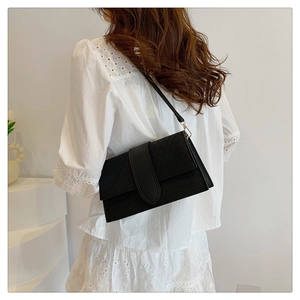 Detail of black rectangular shoulder bag with geometric texture and gold metal hardware