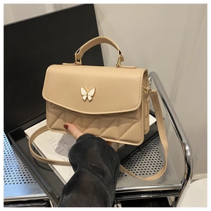 Detail of beige quilted leather mini bag with white enamel butterfly buckle and handle