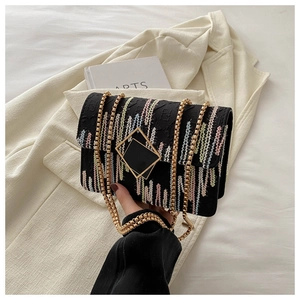 Detail of colorful striped crossbody bag with gold chain and geometric lock on soft blazer