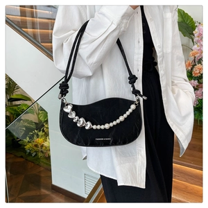 Detail of black crescent shoulder bag with pleated texture and pearl heart chain