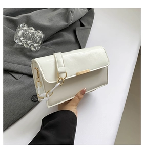 Detail of white leather shoulder bag with gold metal hardware and thick chain strap