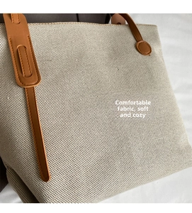 Close-up of beige canvas texture and brown leather handle detail on the bucket bag