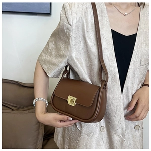 Detailed view of a brown vintage shoulder bag with golden square twist lock on a model