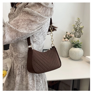 Detail of dark brown quilted shoulder bag with golden chain strap on floral dress