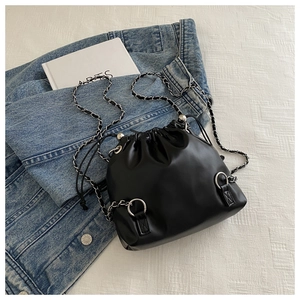 Close-up of black leather bucket bag featuring silver chain strap and drawstring closure