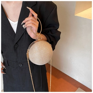 Close-up of golden spherical evening bag with glitter texture and round metal handle