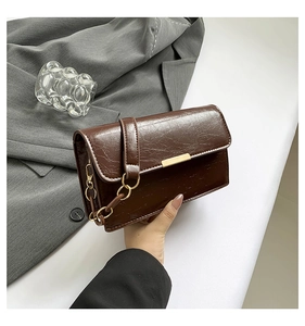 Detailed view of deep brown vintage crossbody bag with glossy cracked texture and gold chain