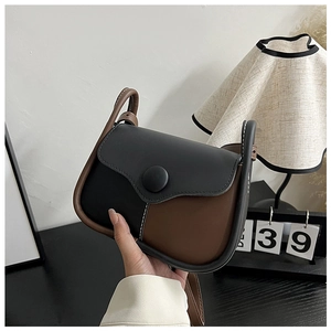 Close-up of bicolor vintage shoulder bag showing fine stitching and decorative round buckle