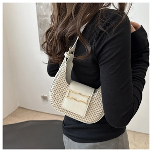 Détail d'un sac bandoulière tissé en demi-lune avec une boucle métallique dorée ondulée