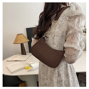Detail of dark brown quilted shoulder bag with golden chain and V-shaped stitching