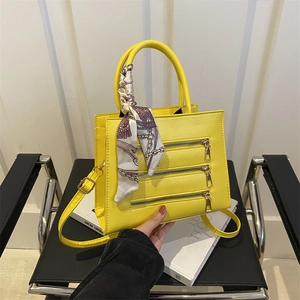 Detail of yellow crossbody bag with three parallel zippers and decorative silk scarf wrap