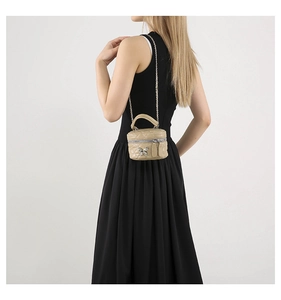 Detail view of beige quilted mini crossbody bag with silver butterfly and chain strap