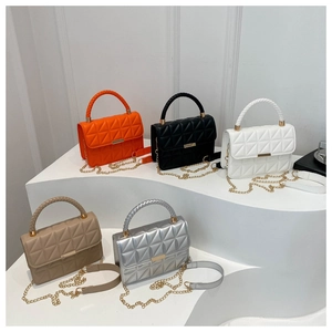 Detail of colorful quilted handbags with braided handles and gold metal chain straps