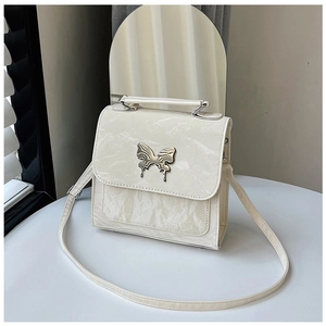 Detailed view of cream textured leather bag featuring a gold butterfly metal clasp