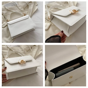 Detail of white structured box bag with gold circular clasp and spacious black interior