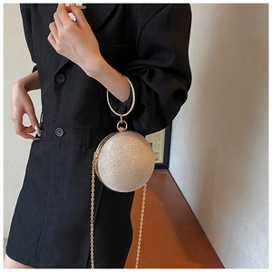 Detail of round glitter evening clutch with gold circular handle and crossbody chain strap