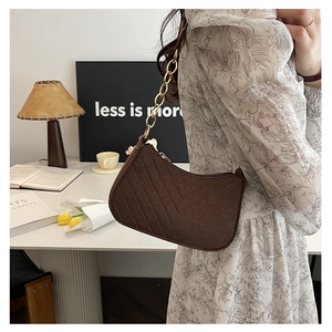 Detail of a brown quilted half-moon shoulder bag with elegant gold metal chain strap