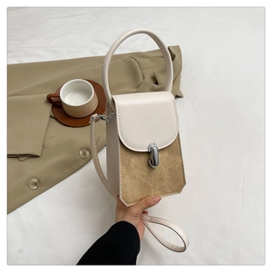 Detail of elegant two-tone leather handbag featuring a circular handle and silver metal lock
