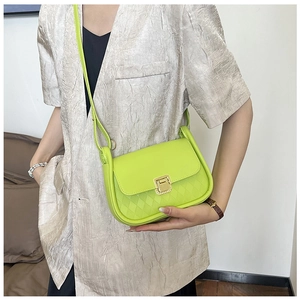 Detail of neon green mini crossbody bag with quilted texture and gold metal buckle