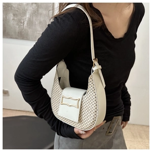 Détail du sac demi-lune avec texture tissée beige et boucle métallique dorée chic