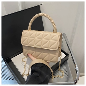 Detail of beige quilted handbag with woven handle and gold chain strap on gift box