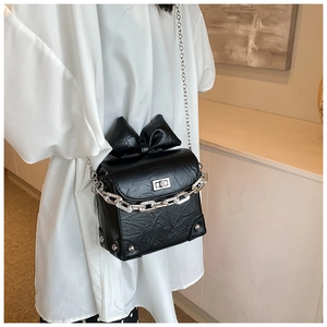 Close-up of black PU leather crossbody bag with bow detail and double metal chains