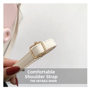 Détail de la boucle dorée réglable sur la bandoulière en cuir crème et rose du sac à main