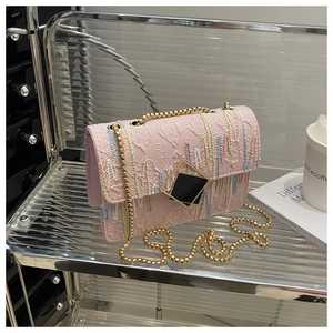 Detail shot of a pink crossbody bag featuring colorful fringe and gold chain strap