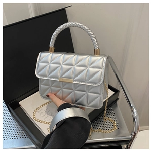 Detail of silver quilted handbag featuring gold metal buckle and woven cylindrical handle