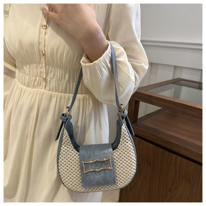 Détail du sac hobo en denim bleu et tissage crème avec boucle dorée élégante en gros plan