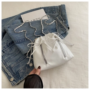Detail of white drawstring bucket bag with dual front zippers and silver chain straps