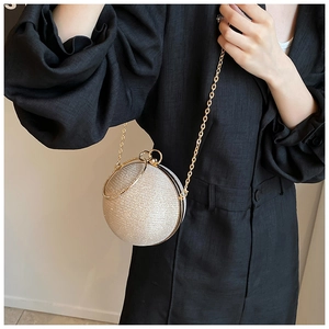Close-up of golden spherical evening bag with glitter texture and metal chain strap