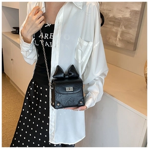 Chic black crossbody bag with oversized bow and silver chain strap shown on a model