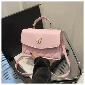Detail of pink quilted handbag with metal butterfly clasp and leather handle