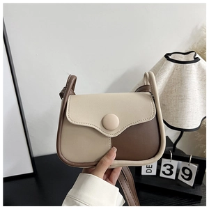 Detail of stylish beige and coffee contrast crossbody bag with round buckle and slim strap